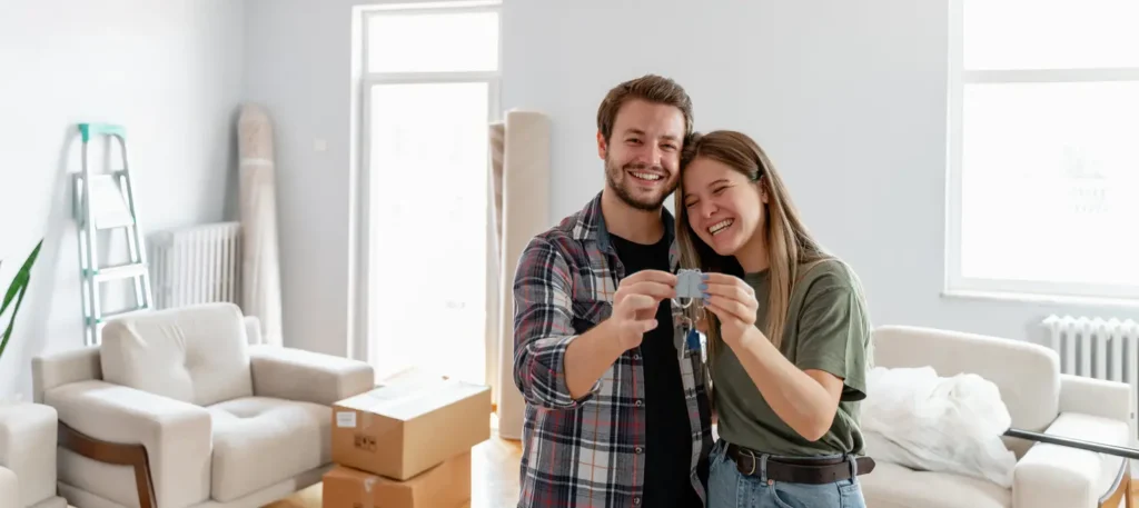 excited-american-young-family-show-keys-to-own-home-happy-couple-buying-first-house-together-smiling-husband-and-wife-purchase-new-property-ownership-concept