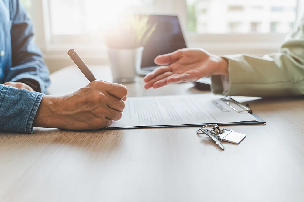 Two people sitting at a desk, going over a rental agreement.