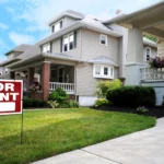 A "for rent" sale is on display in the manicured front lawn of a house.