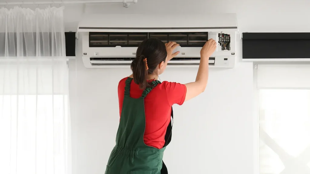 Female technician repairing air conditioner at home