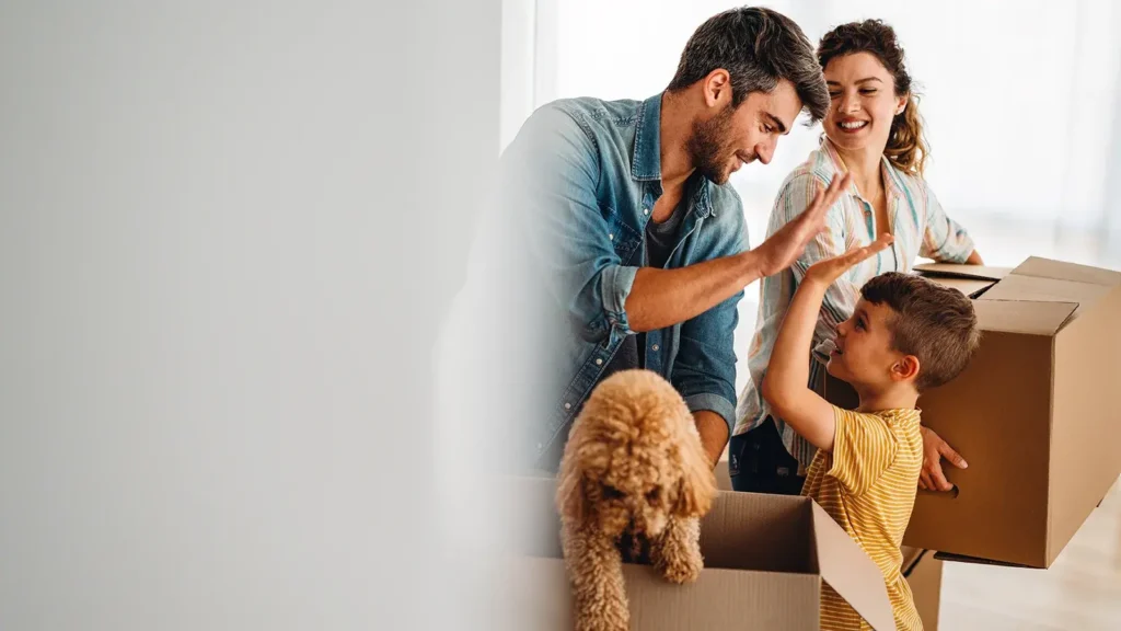 New home, box and parents with child and dog  in new house.