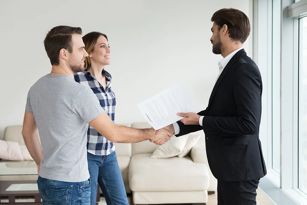 Happy couple shaking hands with their new landlord.