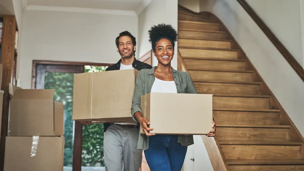 Interracial man and woman owner carrying box for property rental