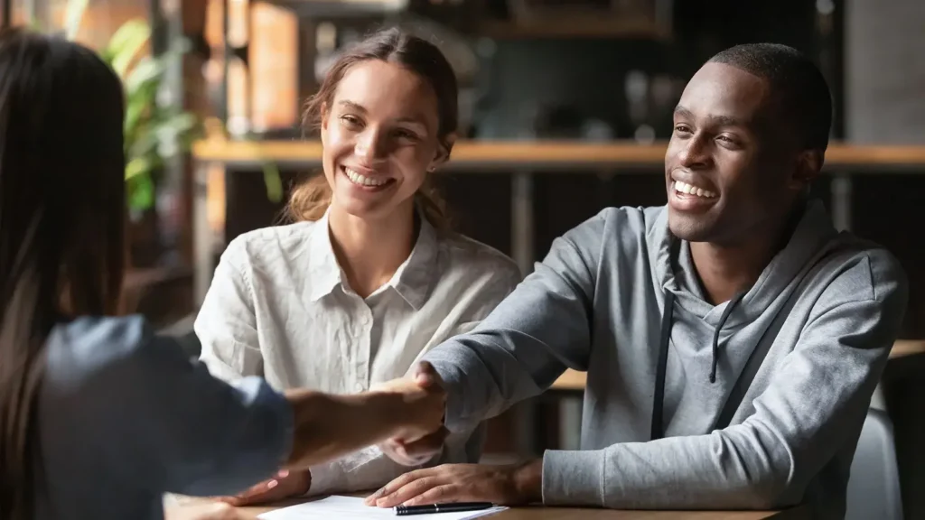 Happy couple shaking hands with a bank manager regarding a mortgage loan