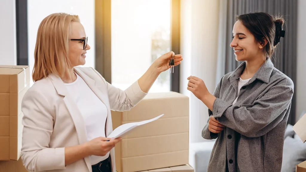 Realtor agent giving a key of apartment to new owner after signed lease agreement.