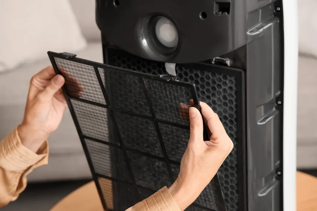 Young woman changing filter in modern air purifier at home