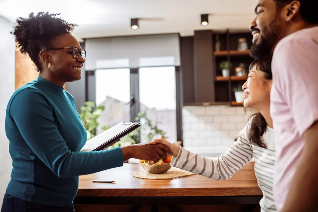 African American boyfriend and Asian girlfriend shaking hands with their real estate agent.