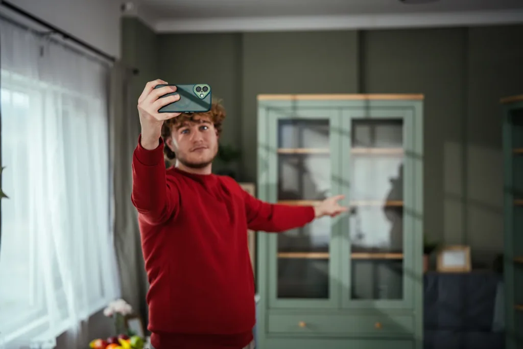 Male v-logger filming home tour video with smart phone