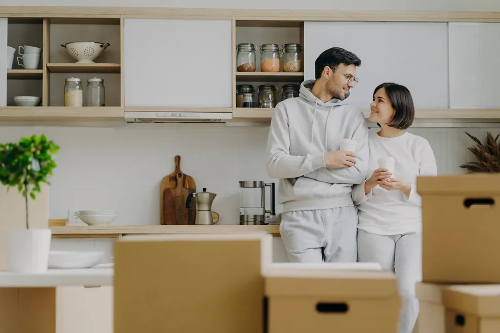 Indoor shot of lovely newlywed couple talk to each other with pleased expressions