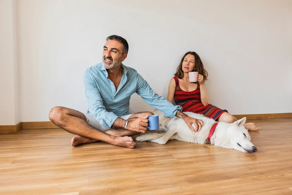 Mature couple on the floor at home with their dog, while having a relaxed coffee