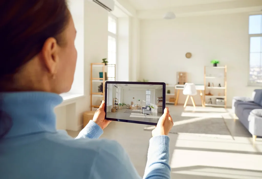Back view of rental agent or female realtor taking photo on smart tablet device of stylish home interior planning to sell apartment.