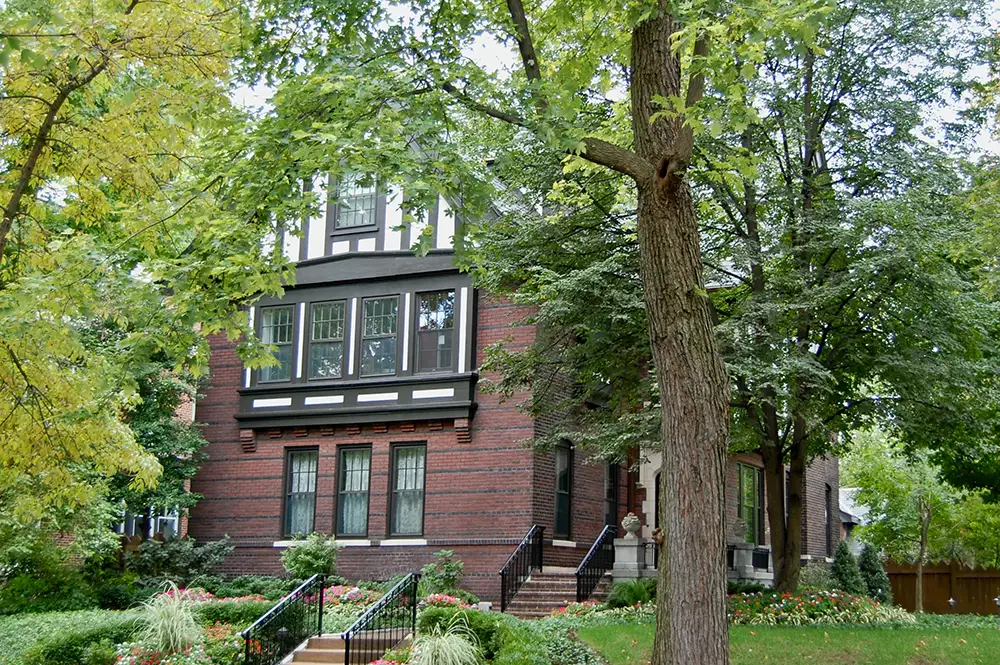 large brick St. Louis residence with lots of trees on the lawn